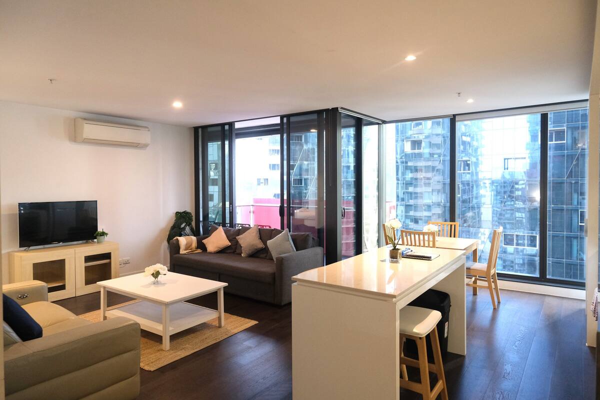 Un salon moderne comprenant un canapé, une table basse, un téléviseur et un coin repas avec des chaises et une table.