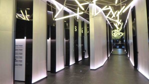 A modern hallway with geometric ceiling lighting and a central open space. - ReadySet Apartments at Manhattan (Melbourne)