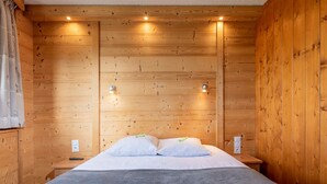 Una stanza in legno con un letto, due comodini e due luci a parete.