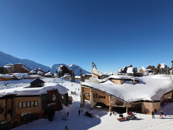 A snow-covered ski resort with wooden buildings, a bistro, and a ski lift.