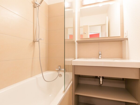 Une salle de bain avec une baignoire, une douche à parois de verre et un lavabo avec un miroir au-dessus.