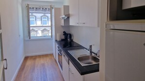 A narrow kitchen with a window, a sink, cabinets, and a stove.