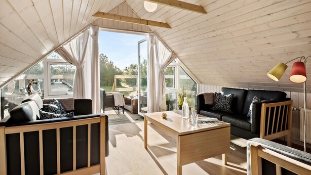 Un loft spacieux avec de hauts plafonds, de grandes fenêtres et un coin salon confortable avec une table et des chaises.