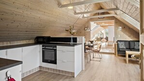 Une cuisine moderne dotée d’un îlot central, d’appareils électroménagers intégrés et d’un coin repas avec un canapé et une table.