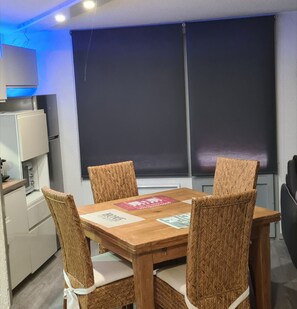 Un coin repas avec une table en bois et quatre chaises en osier.