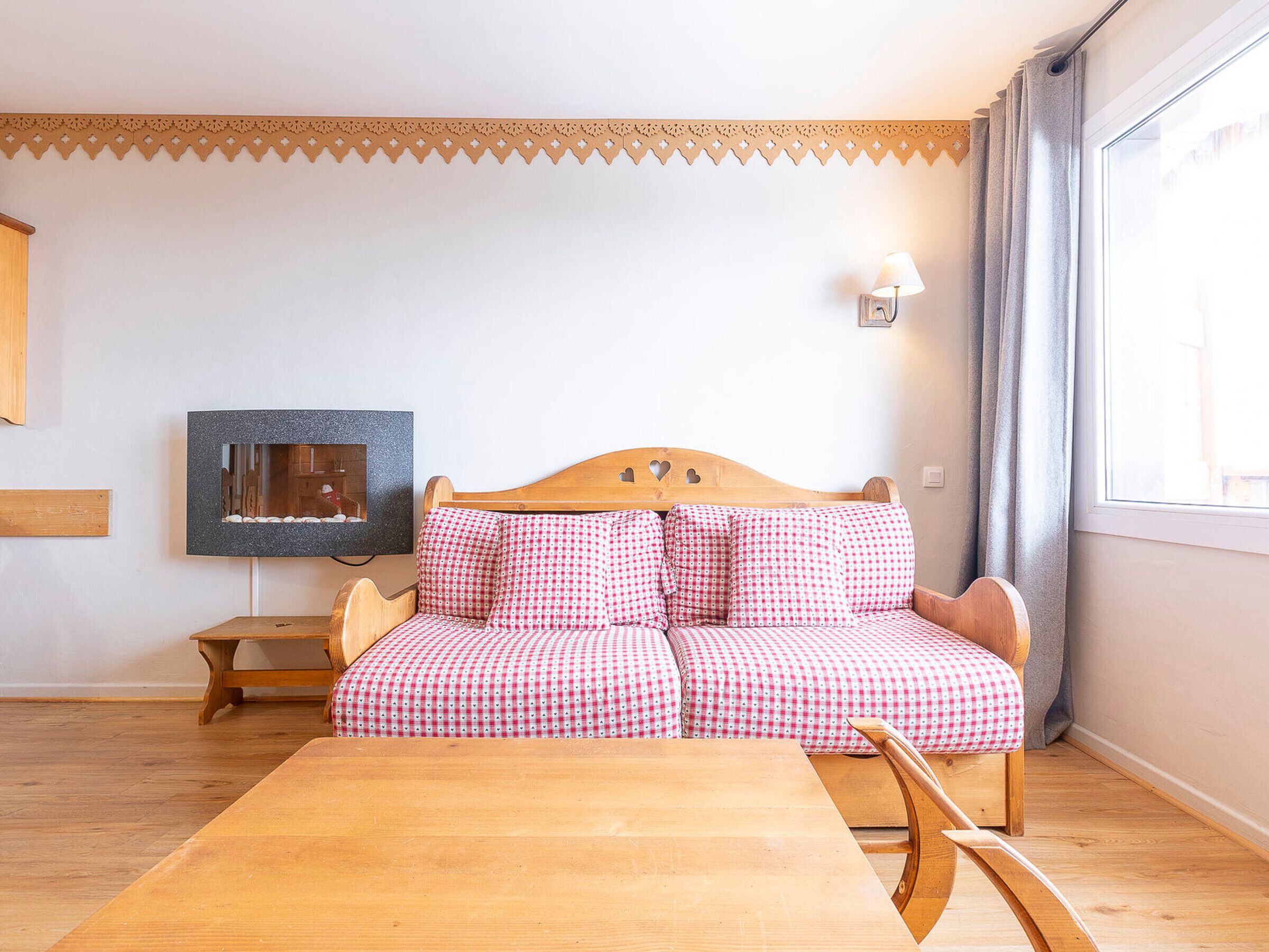A cozy room with a wooden sofa, a small table, and a wall-mounted picture frame.