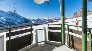 Silla de telesilla suspendida sobre un paisaje nevado de montaña.