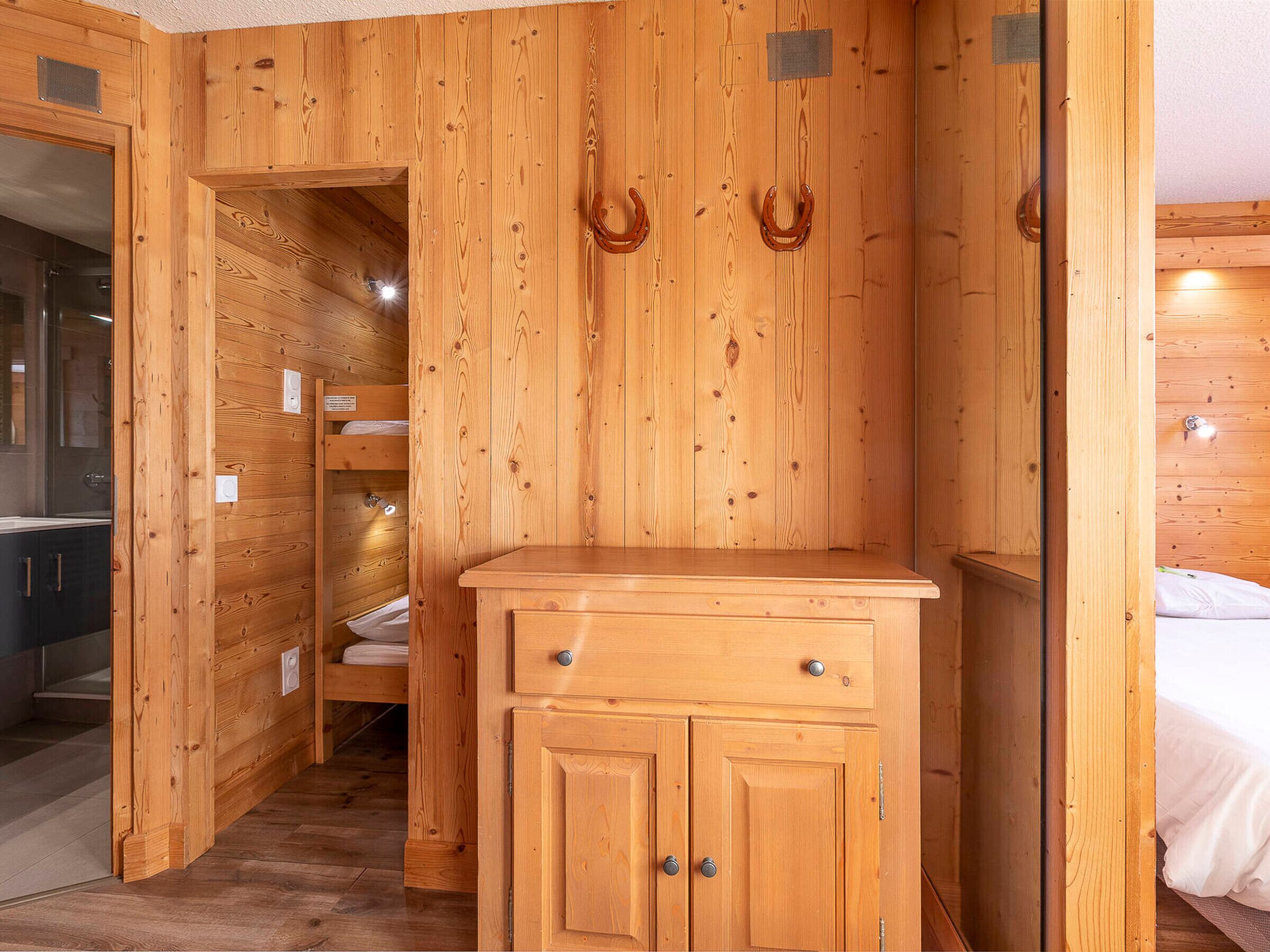 A wooden interior with a wooden cabinet, a bed, and a bathroom with a glass shower.