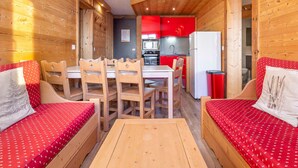 A cozy cabin interior with wooden walls, a dining area with a table and chairs, and a kitchenette with red cabinets. - Renovated apartment for 8 in Avoriaz, mountain charm and modern (Avoriaz)