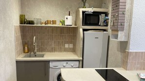 A compact kitchen with a washing machine, a microwave, and a sink.