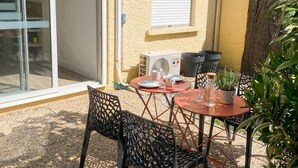 A patio with outdoor furniture, a sliding glass door, a white air conditioning unit, and a window with blinds.