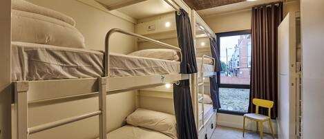 A bunk bed room with a window, a chair, and a door.