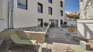 Un edificio moderno con un patio que ofrece asientos al aire libre y una pequeña zona de jardín.