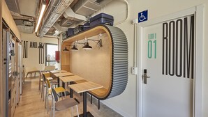 Una habitación moderna con una pared curva distintiva, una puerta con la etiqueta “ROOM 01” y un letrero indicando acceso para sillas de ruedas.