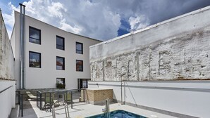 Un edificio moderno con piscina, fachada blanca y varias ventanas.