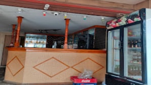 A small, enclosed room with a counter, a refrigerator stocked with beverages, and a door leading to another area. - MeroStay 191 Hotel City Pvt. Ltd. (Kathmandu)