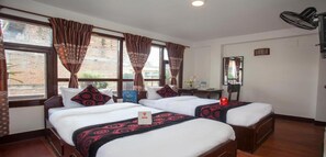 A hotel room with two beds, a desk, a chair, a mirror, and a window with curtains. - MeroStay 191 Hotel City Pvt. Ltd. (Kathmandu)