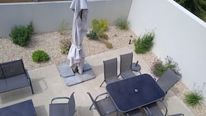 An outdoor patio with a table and six chairs, surrounded by small plants and a gravel area. - Cabellou Vras (Concarneau)