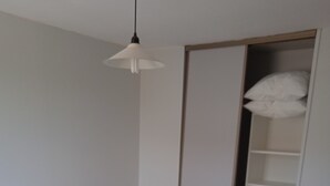 A bedroom with a bed, a nightstand, a wardrobe, and a hanging light fixture. - Cabellou Vras (Concarneau)