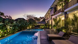 A swimming pool with lounge chairs, surrounded by lush greenery and a building with balconies. - Cove Tevana (Keroboken Kelod)