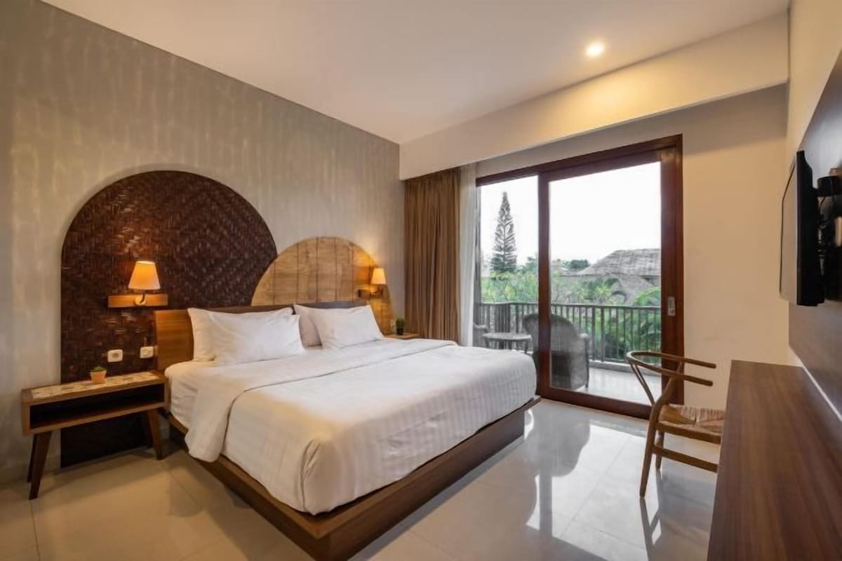 Une chambre d’hôtel avec un grand lit, une table de chevet, un bureau et un balcon avec vue.