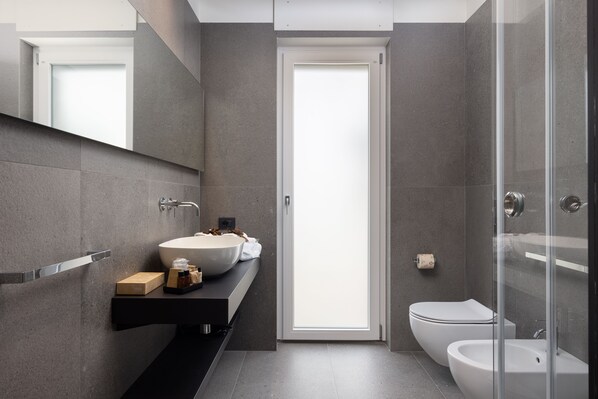 A modern bathroom with a large mirror, a sink, a toilet, and a shower area. - B21 Lifestyle Hotel (Bari)