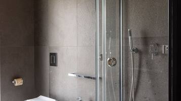 A modern bathroom with a glass-enclosed shower, a bidet, and a toilet.