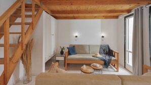 Une pièce avec un plafond en bois, un canapé, une petite table et un escalier.