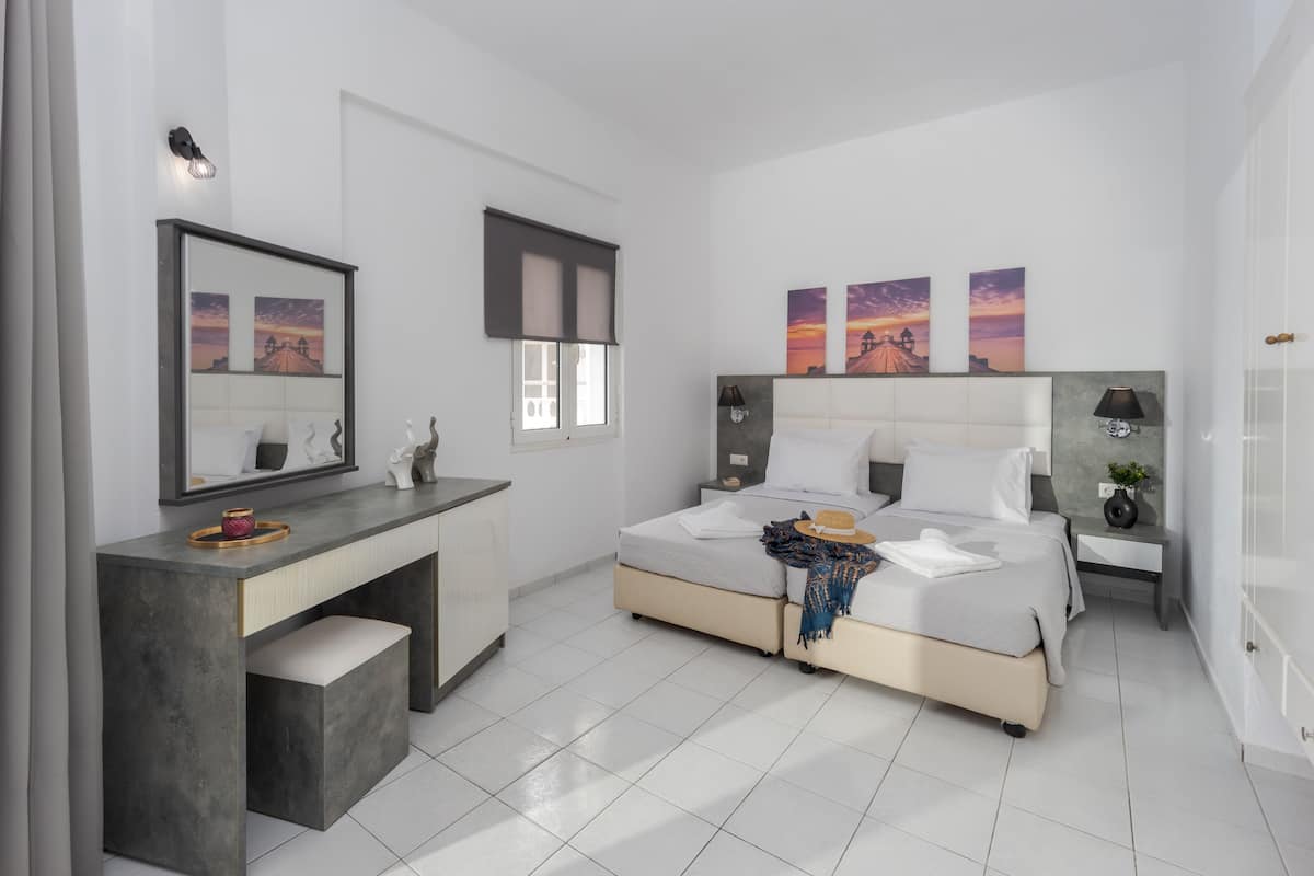 Un dormitorio moderno con cama, mesitas de noche, un escritorio y un espejo grande.
