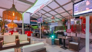 Un espace de détente moderne avec des meubles en osier, un bar appelé « Energy Bar » et un écran de télévision.