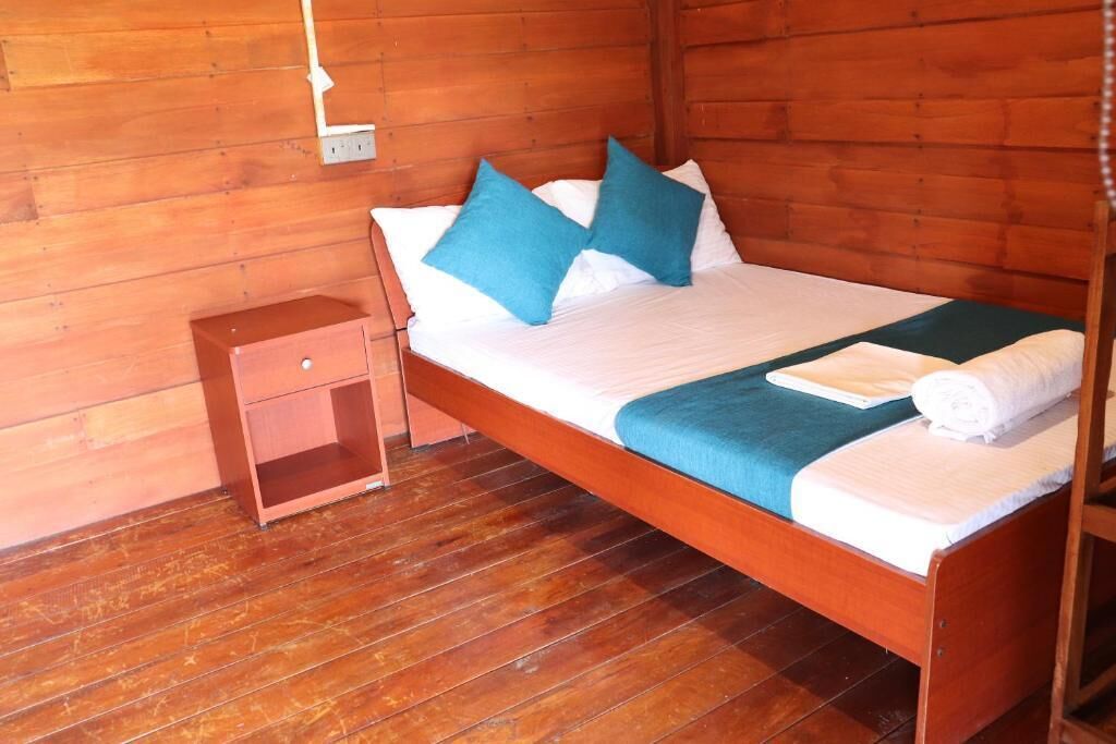 A wooden bed with blue and white bedding, a wooden nightstand, and a wooden floor.