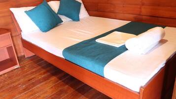 Un lit en bois avec une literie blanche et turquoise, un plaid vert et un oreiller blanc.