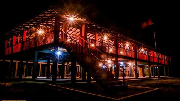 A building with a red exterior and multiple levels, featuring a prominent staircase and a covered area with a roof.