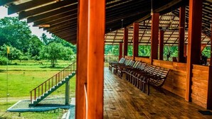 A covered outdoor seating area with wooden benches and a staircase leading to a grassy area.