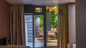 A room with a sliding glass door leading to an outdoor area with wicker furniture and greenery.
