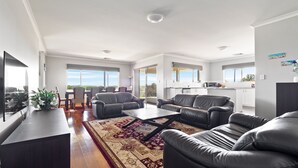 A modern living room with leather sofas, a coffee table, and a dining area with chairs. - The Dunes *Pet Friendly* Sea Retreat Busselton (Wonnerup)