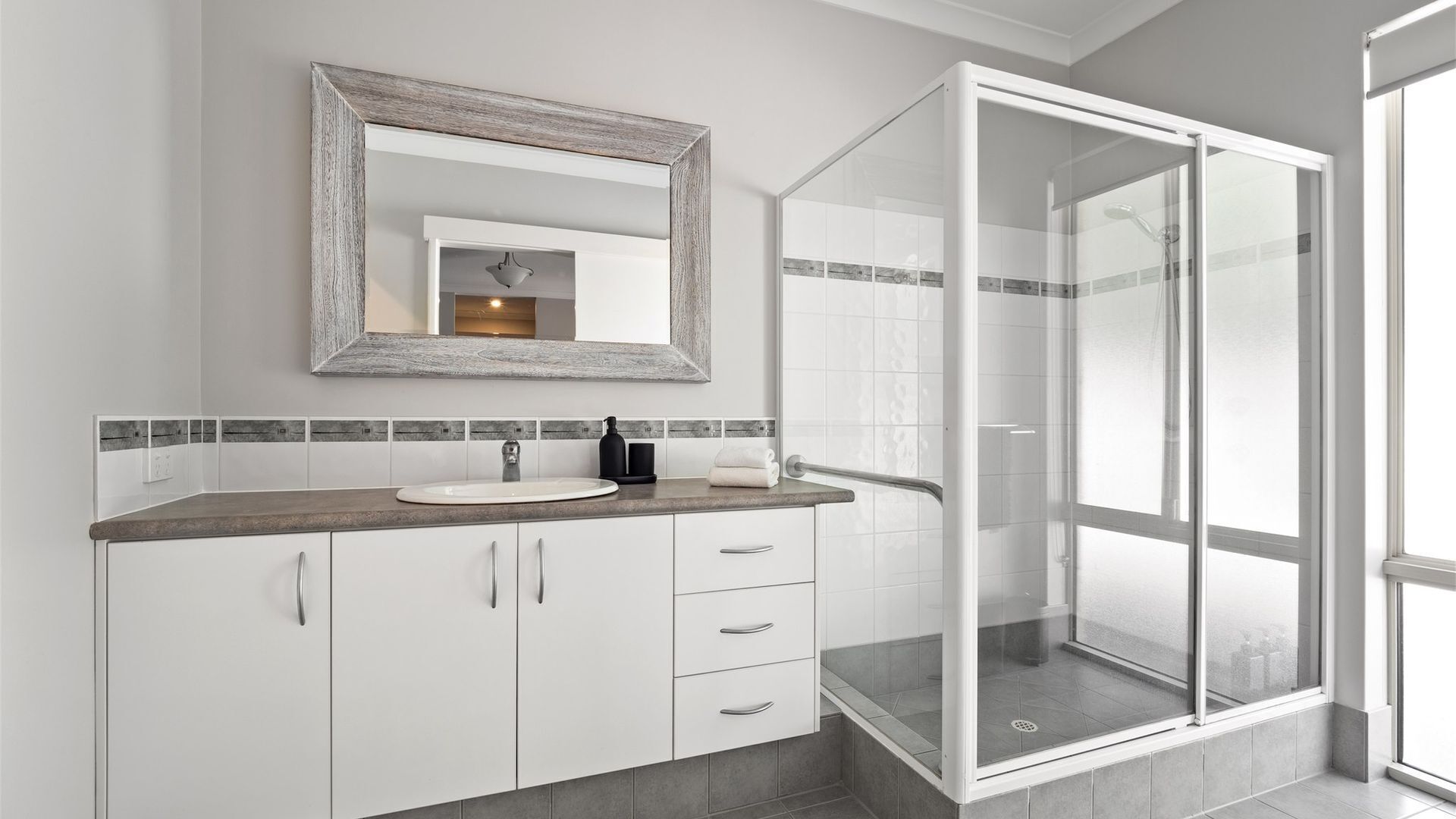 Une salle de bain moderne avec un grand miroir, un lavabo et une douche à parois de verre.