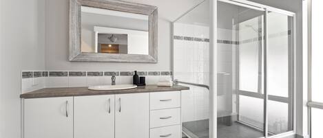 Une salle de bain moderne avec un grand miroir, un lavabo et une douche à parois de verre.