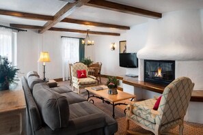 A living room with a sofa set, a wooden coffee table, a fireplace, and a television.