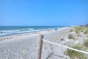 A beach with a wooden fence, sandy dunes, and the ocean.