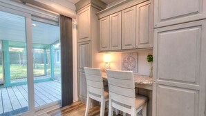 A kitchen with wooden cabinets, a dining area with two chairs, and a view through large sliding glass doors. - Discover Sea Glass: a cozy Oak Island retreat with 3 bedrooms and pet-friendly amenities! (Oak Island)
