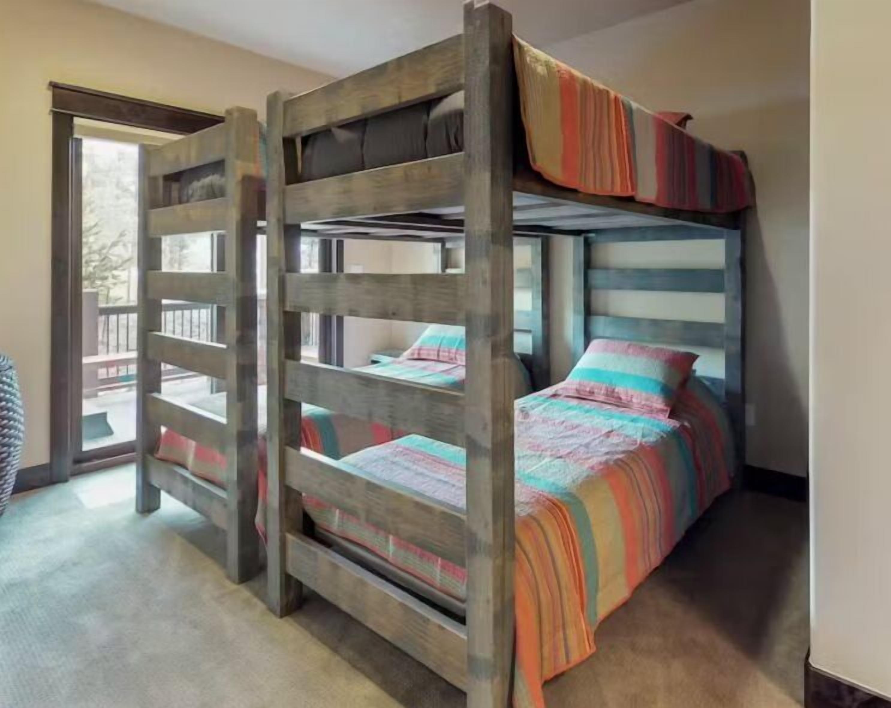 A bunk bed with a wooden frame and colorful bedding.