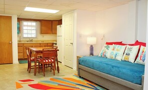 A compact living space with a kitchenette, a dining area, and a bedroom with a sofa and colorful pillows. - The Knotty Hooker - Classic 4BR Soundfront Home - Pet Friendly! (Surf City)