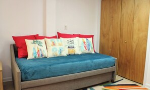 A bed with a blue cover, multiple pillows with tropical designs, and a wooden wardrobe in the background. - The Knotty Hooker - Classic 4BR Soundfront Home - Pet Friendly! (Surf City)