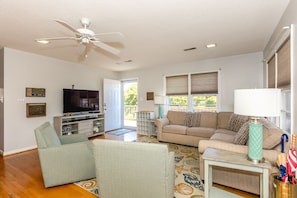 A living room with a ceiling fan, a television, a sofa, and a coffee table.