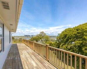 A wooden deck with a railing, overlooking a body of water and a bridge. - The Knotty Hooker - Classic 4BR Soundfront Home - Pet Friendly! (Surf City)