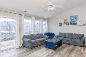 A living room with two grey sofas, a blue coffee table, and a ceiling fan.