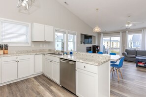 A modern kitchen with white cabinetry, a stainless steel dishwasher, and a granite countertop. - Shore Is Nice - 4BR Townhouse with Easy Beach Access! Pet Friendly! (Surf City)