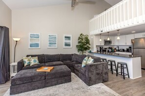 En moderne stue med en modulsofa, et sofabord og en stor potteplante.