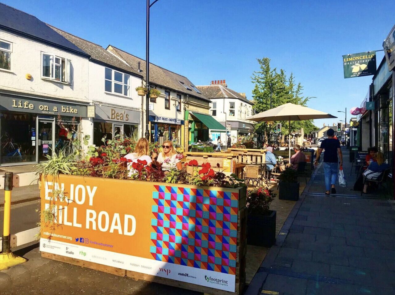 Una calle con comercios y un letrero que dice "ENJOY STILL ROAD".